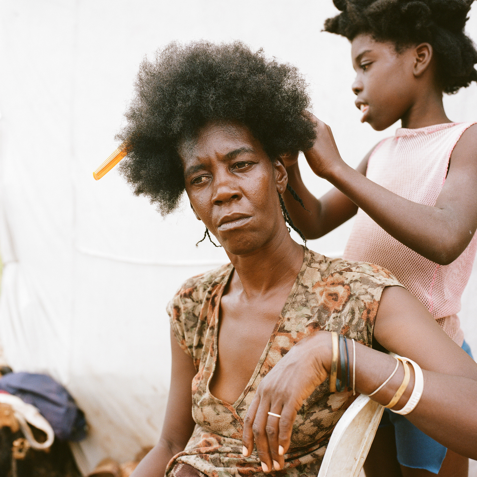 Emani Escaliste, 35 years old, has her hair done by one of her daughters, Sara Noel, 6 years old, at displacement Camp 3 in Anse-a-Pitres, Haiti where she now lives with her five children. She came to the camp from La Mercedes, Dominican Republic after h