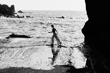 bw woman with white trousers walking profil near the ocean