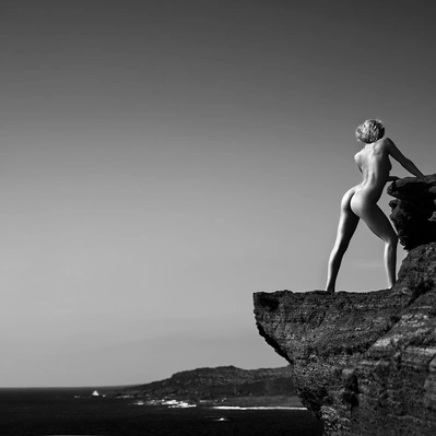 Barefoot on the precipice, she surveys the endless blue, a solitary figure against the backdrop of the sea.