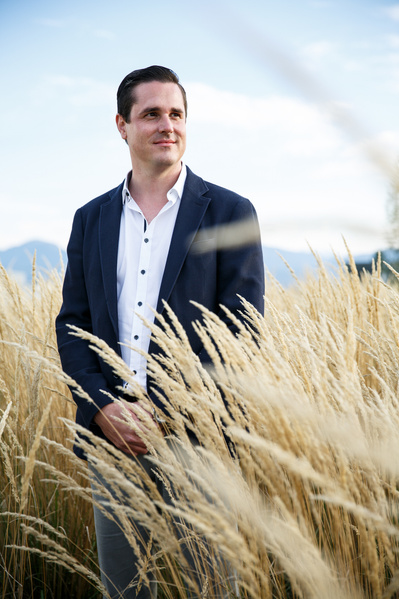 A man in a suit looks to his left side between high yellow grass
