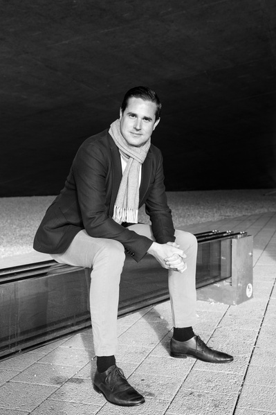 A man in a suit sits on top of a bench made of glass