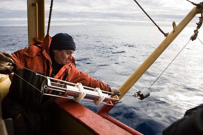 A man on the deck of a vessel brings up a probe that was in the Ocean that can be seen in the background.