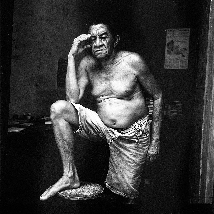 Black and White photograph of a shitless man holding his head. Shot on a Rolleiflex using Kodak Tri-X
