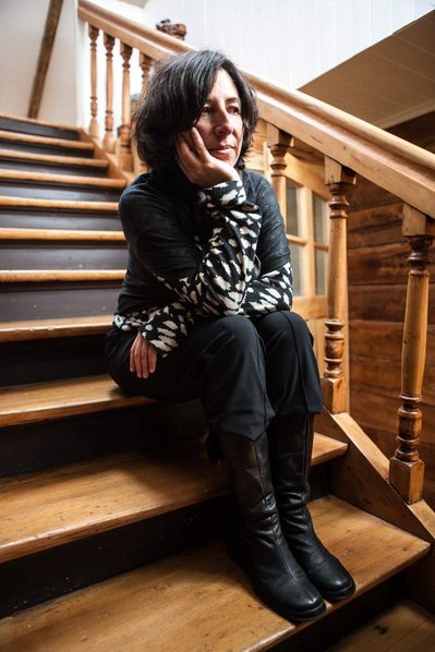A woman sits on a wooden staircase