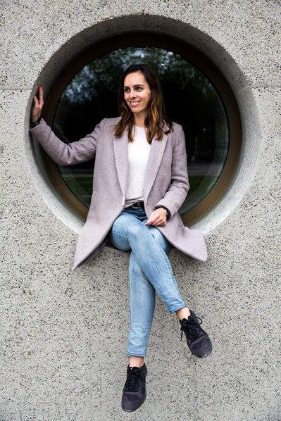 A woman sits in a round window with her  legs crossed.