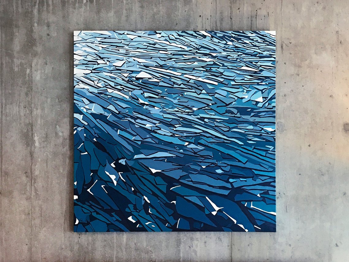 A canvas painting shows ice shards found on Lake Ontario in the winter. The blue acrylic gradients appear extra vibrant against an industrial, grey, concrete wall.
