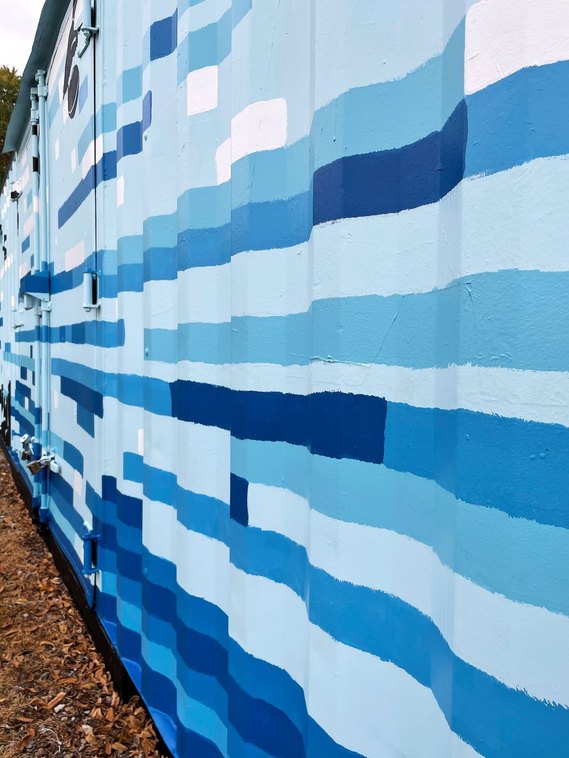 The wavy structure of the metal container wall adds movement to the blue water lines. 