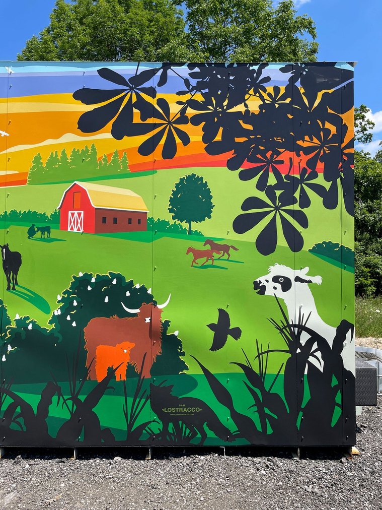 The right side of the mural shows an alpaca, highland cows, running horses, and a red barn. Below is Pam Lostracco's logo on top of a black silhouette of a fox. 