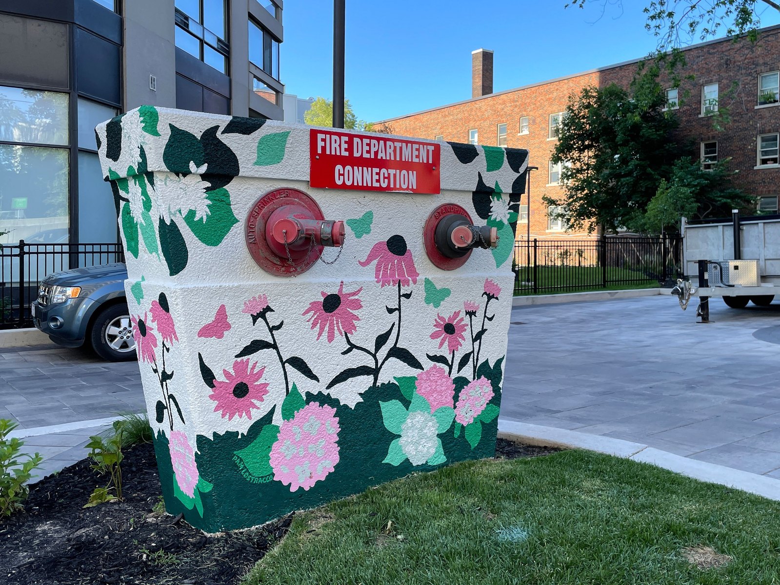 A large fire hydrant sits in the front yard of a condo and is made beautiful with a floral pattern. 