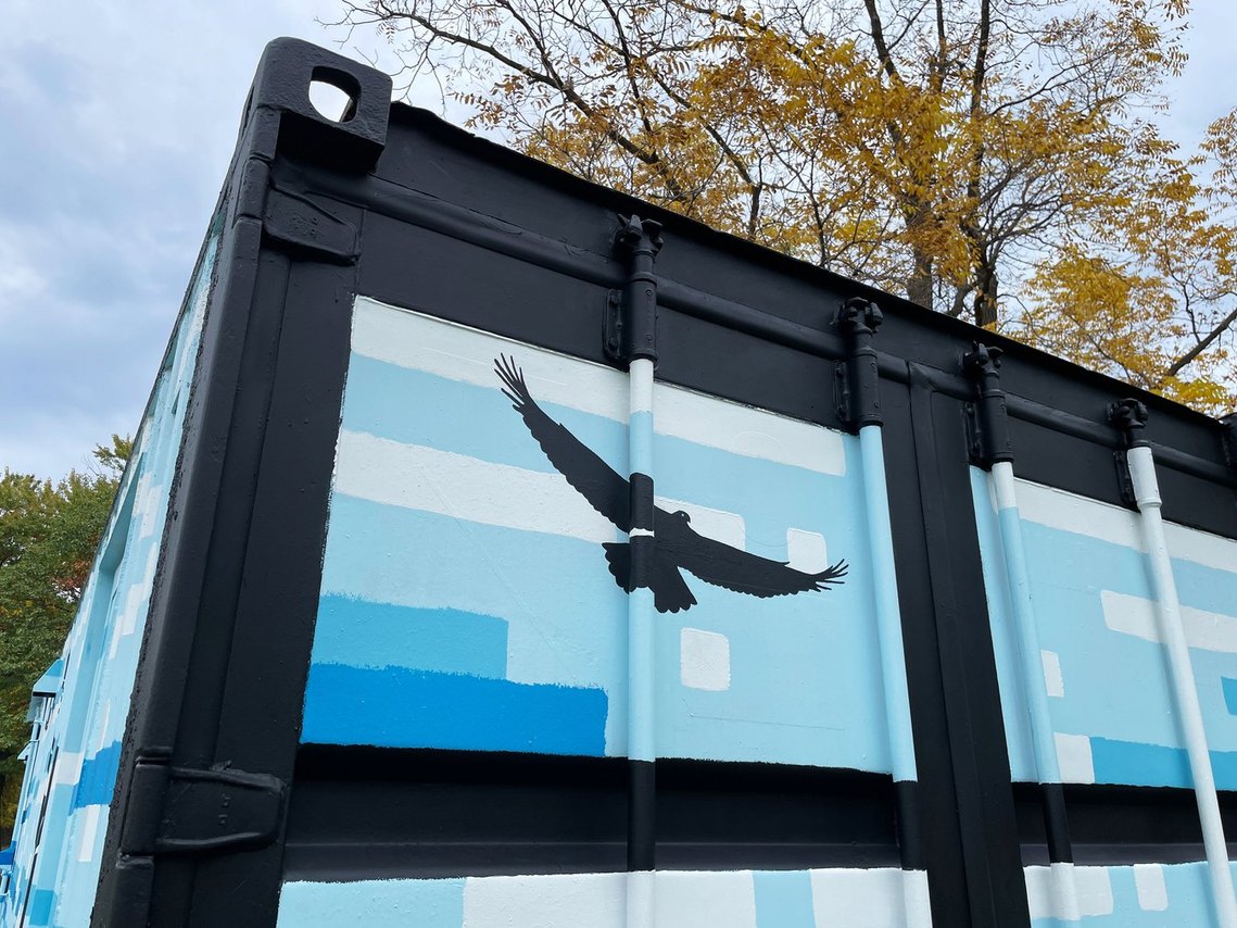 Detail of a hawk flying high above in an abstract painted blue sky. 
