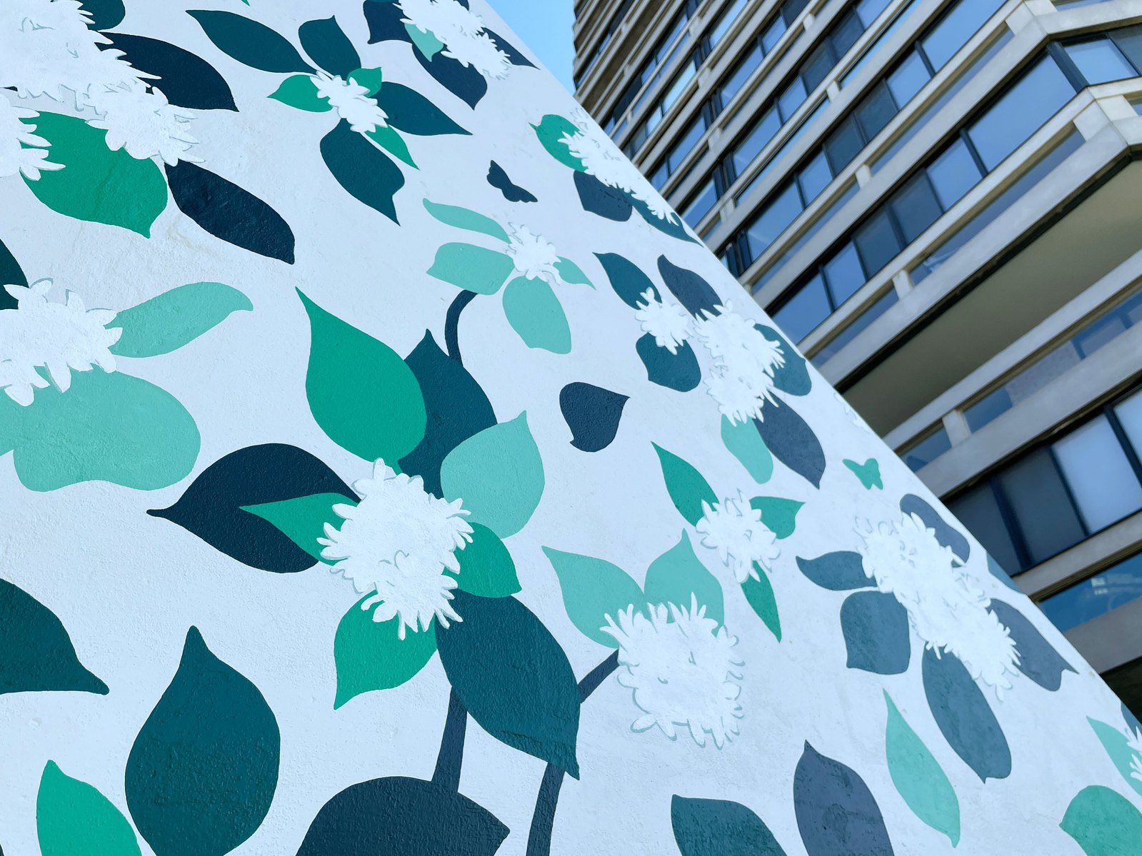 Detail of dogwood leaves and blossoms painted onto a concrete wall. 