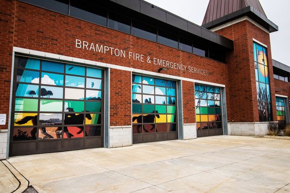 An angled shot of three garage doors on a fire station with a mural depicting Brampton's agricultural history. 