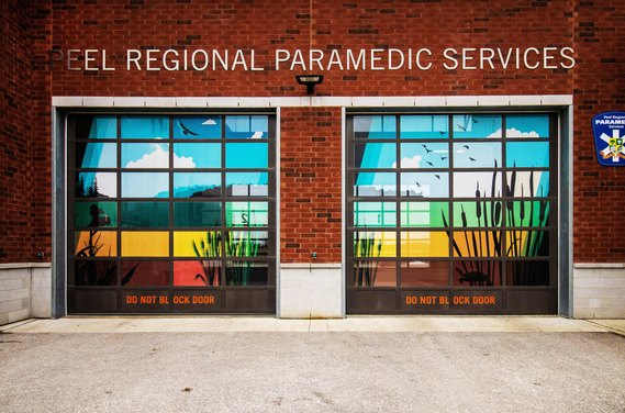 Two fire station garage doors with vibrant artwork in blues, greens, and reds that match the surrounding environment. 