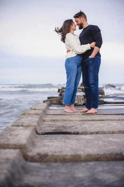 Milwaukee engagement photographer.  Milwaukee Wedding Photographer.  Engagement shoot at Atwater Beach in Milwaukee, Wisconsin.  Couple stands on pier overlooking the lake.