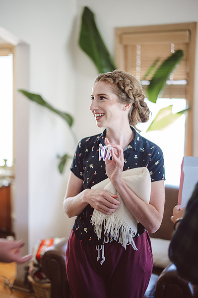 Bride on wedding day during bridal prep, holding onto sunglasses and smiling with house plants in the background.  Milwaukee, Wisconsin wedding.