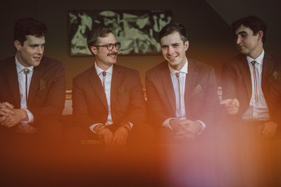 Candid photograph of groom and groomsmen during groom prep on wedding day in Milwaukee, Wisconsin.  Color photograph with print of La Guernica in background by Pablo Picasso.