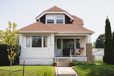 Bridal prep in the house of the couple in Milwaukee, WI on wedding day.  color photo, wide shot of house and front yard.