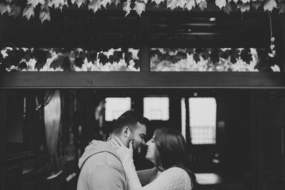 Milwaukee engagement photography session in the Riverwest neighborhood.  Photograph is in black and white, and the photograph is in Amorphic Beer's beer alley.  Couple are touching foreheads and laughing and smiling.