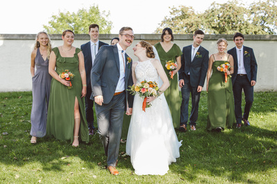 bridal party photograph in color of bride and groom walking in front of the bridal party during their wedding day in milwaukee wisconsin at south shore terrace.  everyone is laughing.