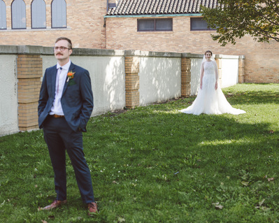 first look for bride and groom.  groom faces the camera while the bride walks up behind him on their wedding day at south shore terrace in milwaukee wisconsin.
