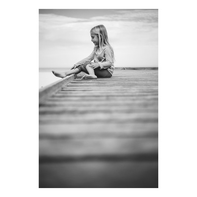 family photography of young girl playing at the beach in Milwaukee, Wisconsin sitting on the boardwalk.