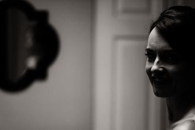 black and white candid photo of bride to be with door and mirror in the background.