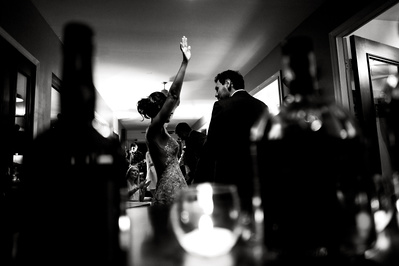 black and white candid dance photograph of bride and groom with bottles of liquor in the foreground.
