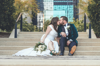 bride and groom kissing on the steps in a chicago park, maggie daley park, in a candid photograph.