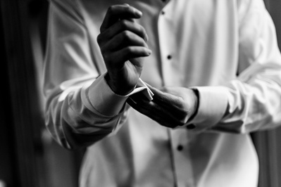 groom fixes his cufflinks during wedding preparation.