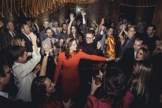 chicago wedding couple dances on the dance floor on their wedding day.  the dance floor is full and lights from the ceiling streak across the frame.  couple is smiling and people have their hands in the air. Lacuna Lofts, Chicago.