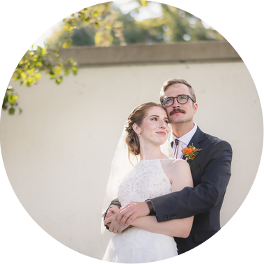bride and groom on their wedding day in Milwaukee at South Shore Terrace.  Groom stands behind bride with his arms wrapped around her while they look into the distance and smile.