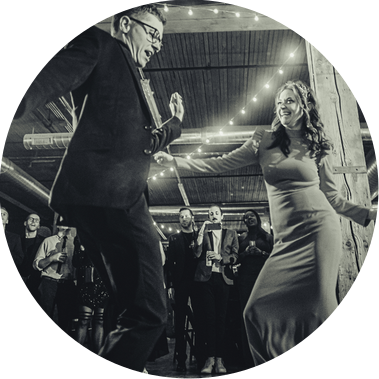 couple dancing on their wedding day, groom wearing a suit, bride wearing a dress, black and white dancing with guests in the background and lights hanging from the ceiling.  chicago wedding, photograph taken by Patrick Betcher of Betcher Photo.