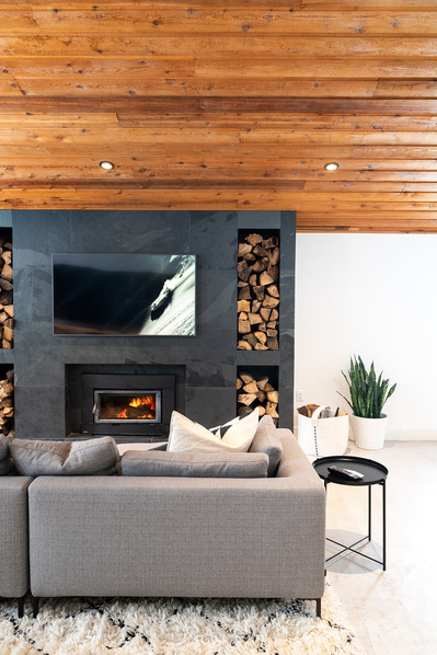 Interior Photography by commercial photographer Heather Goldsworthy. A bright, Scandinavian design inspired chalet living room with rich wood ceiling and custom slate fireplace