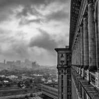 Iconic Ford Michigan Central Station standing tall amidst a dramatic stormy sky, a symbol of revitalization and resilience in black and white.
