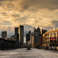 Mesmerizing Detroit skyline captured at street level during a stunning sunrise. Majestic clouds adorn the sky, while the iconic Little Caesars Arena, home of the Detroit Red Wings, stands proudly in the foreground, creating a breathtaking composition