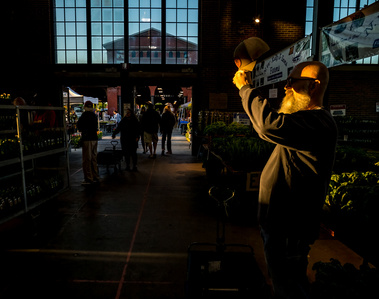 Embrace the vibrant atmosphere of Detroit's  Eastern Market Farmer Market. In this captivating photo, a man shields his face from the radiant sun, casting intriguing shadows amidst the bustling market. The interplay of bright light and deep shadows.