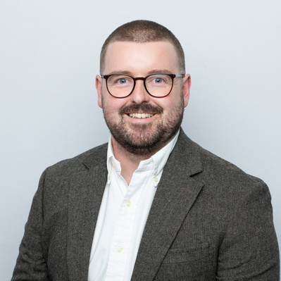 Studio headshot portrait on a neutral grey backdrop for corporate use