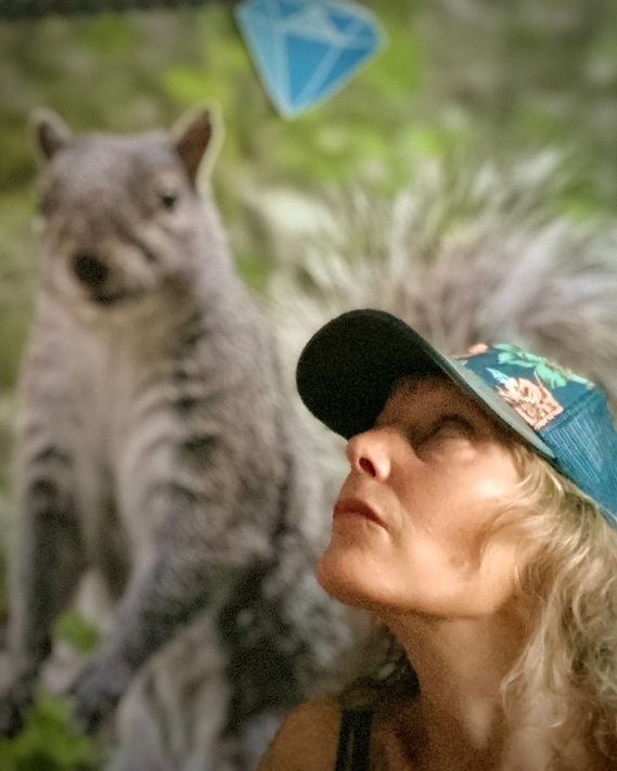 Eliesha Grant self-portrait  iPhone 11 Pro Max with a 5 foot working print of a squirrel and diamond emoji.
