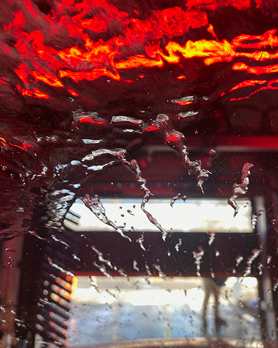Light at the end of the tunnel with red and purple chemicals, soapy water and colored lights in the drive-in car wash.
