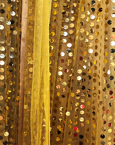 A gaudy shiny dress at a wedding made of golden sequins and taffeta. 
