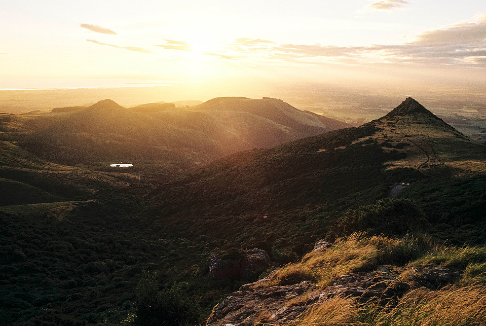 The Port Hills illuminated by a golden sunset, with rich contrast and deep shadows. Captured on 35mm film using the Canon AE-1 Program, enhancing the natural landscape tones.