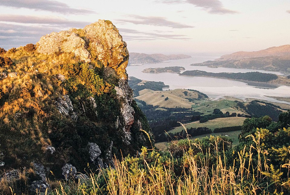 A rock face in the foreground with Lyttelton and its surrounding bays stretching into the distance. Shot on 35mm film with the Canon AE-1 Program and Tokina 28mm f/2.8 FD lens.