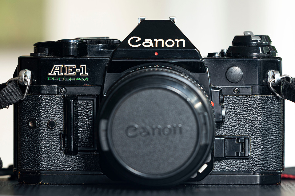 The Canon AE-1 Program with a Tokina 28mm f/2.8 FD lens, showing its classic silver and black SLR design. A lightweight 35mm film camera ideal for all photography styles.