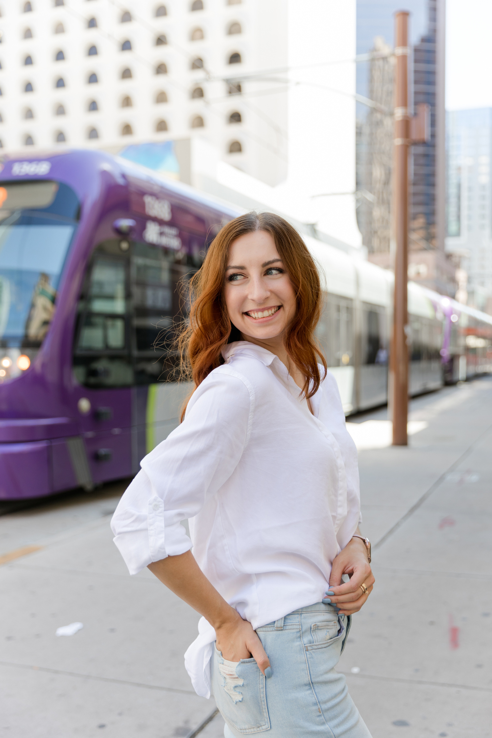 A woman on the street of downtown phoenix in Arizona with the metro speeding by behind her