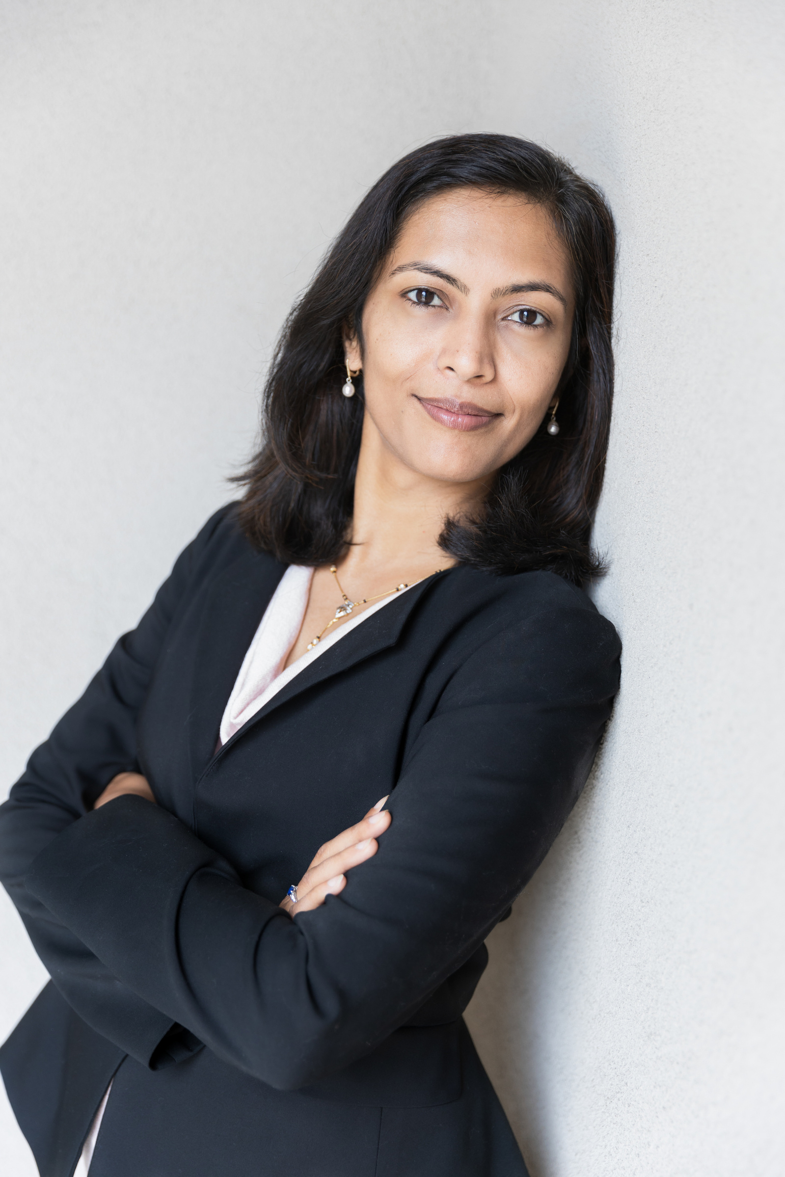 A woman leaning up against a wall for her corporate headshot