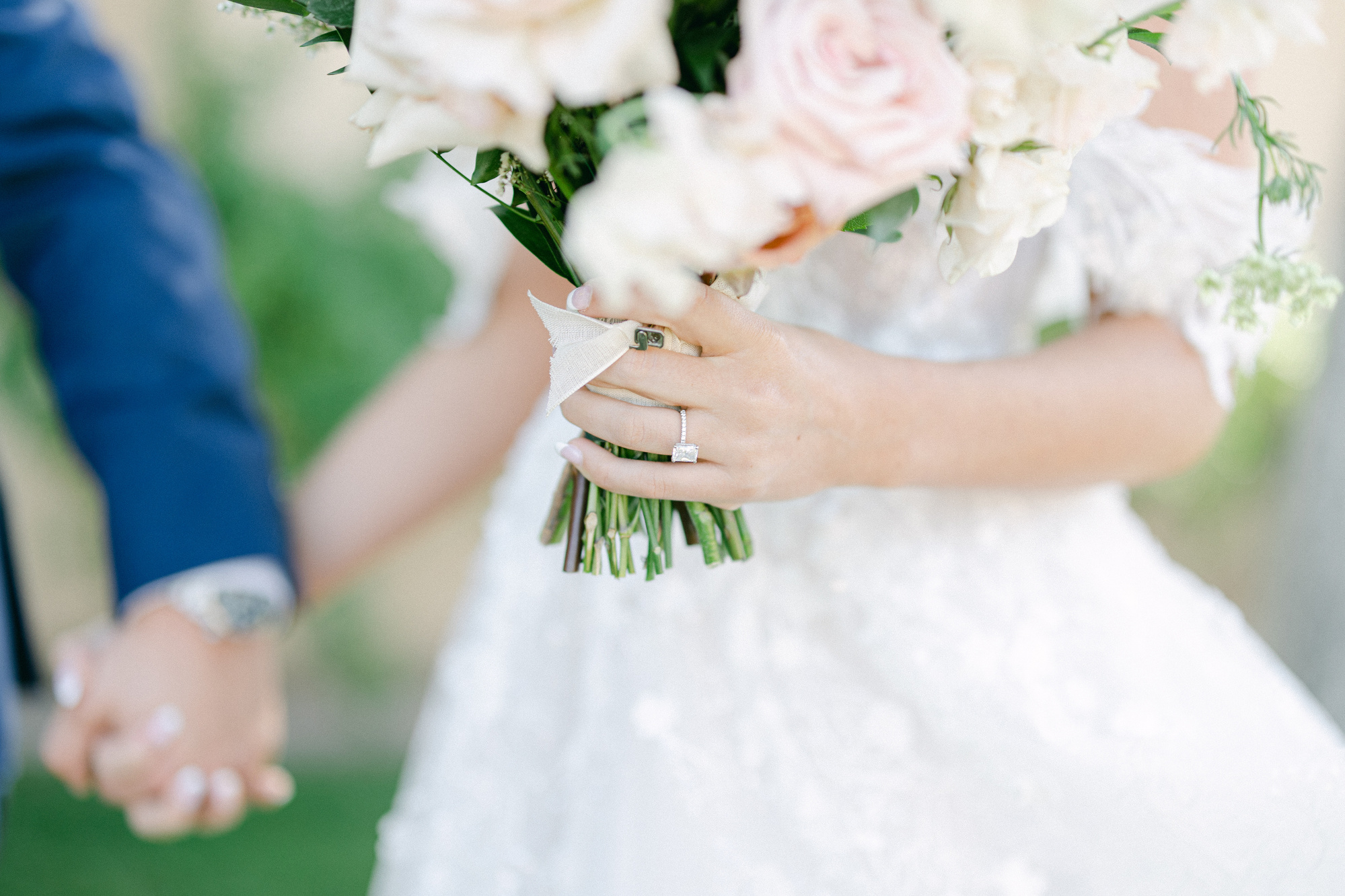 A bride on her wedding day holding her bouquet and displaying her engagement ring