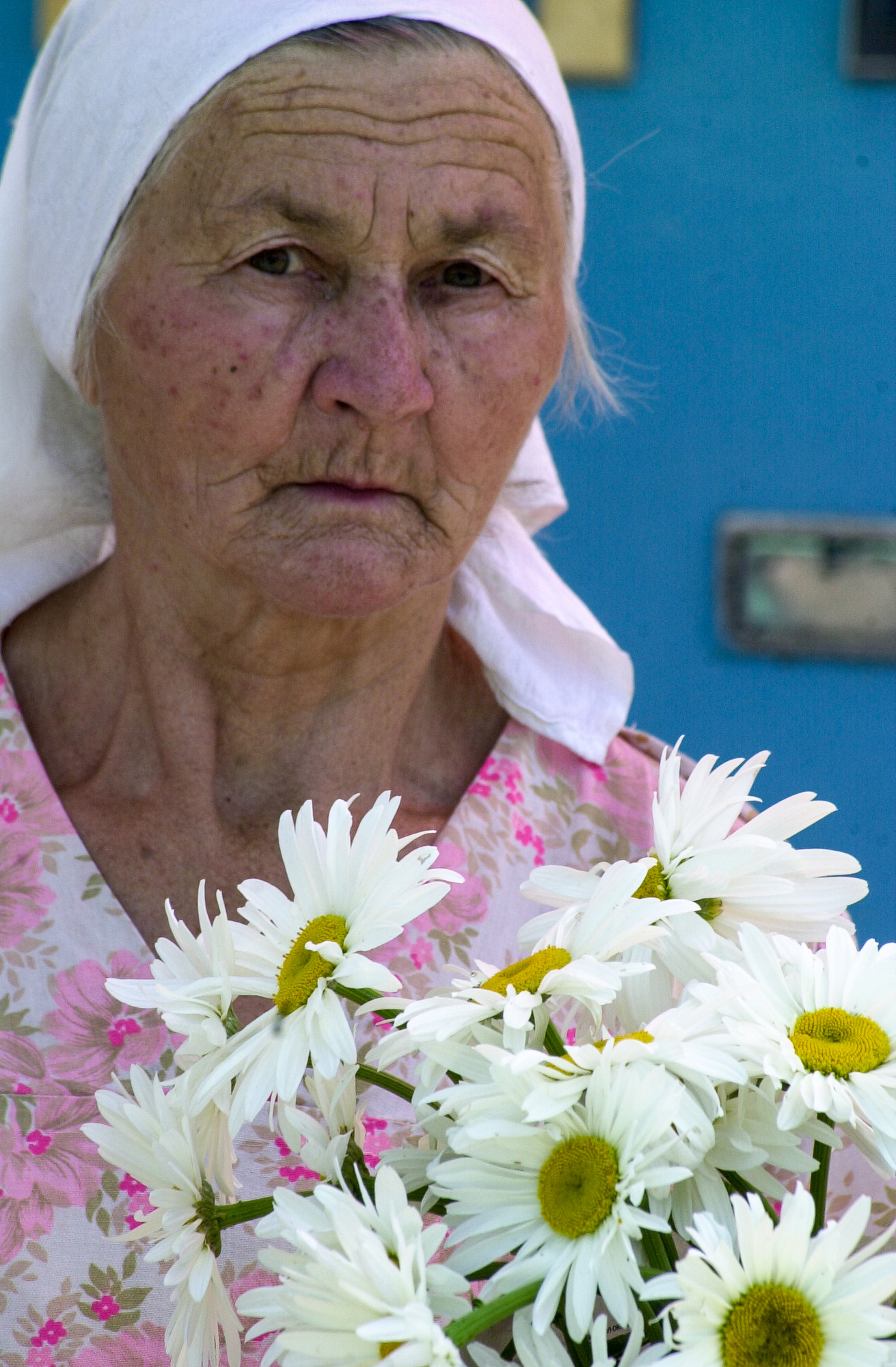 Colour portrait of a woman with headscarf selling marguerites on the street in Almaty, Kazakhstan.