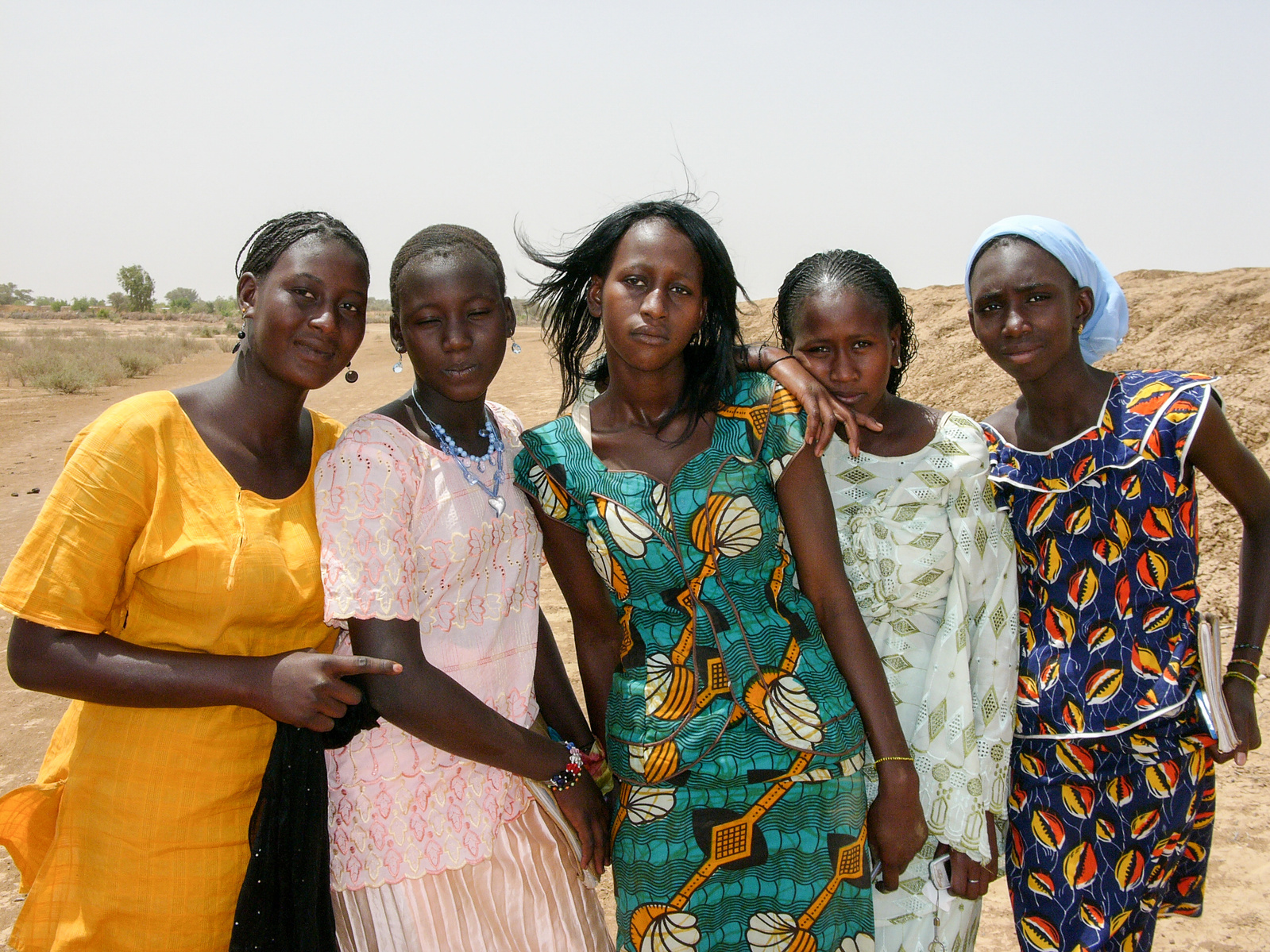 Five girls in colourful dresses, on their way home from school. Mauritania.