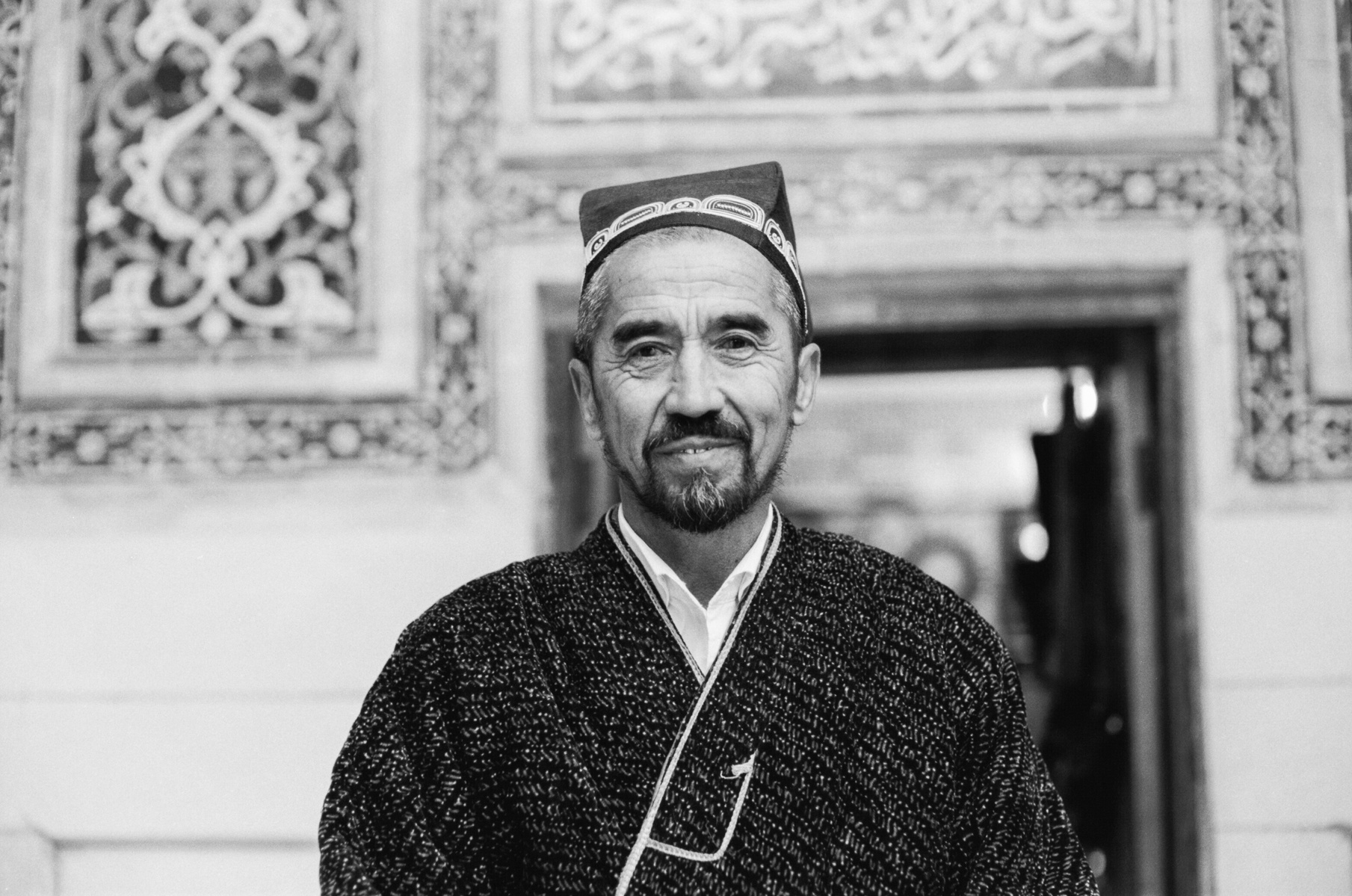 A black and white photograph of a man working as a calligrapher for tourists in Samarkand, Uzbekistan.