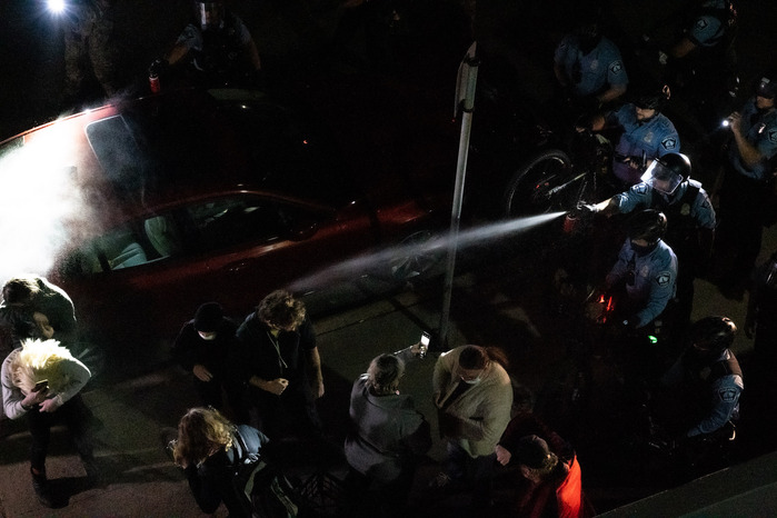 Two Minneapolis Police officers deploy a chemical irritant spray at protesters near Interstate 94 in Minneapolis, Minn., on Wednesday, Nov. 4, 2020. Protesters on the freeway were ordered to sit and be processed for arrest, they held a dance party instead